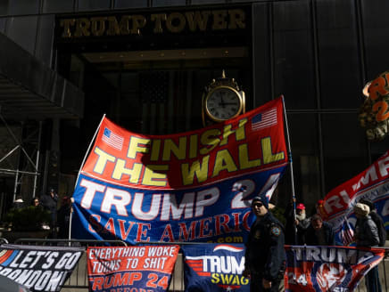 An NYPD officer walks past supporters of former President Donald Trump holding signs outside of Trump Tower on March 20, 2023 in New York, New York.