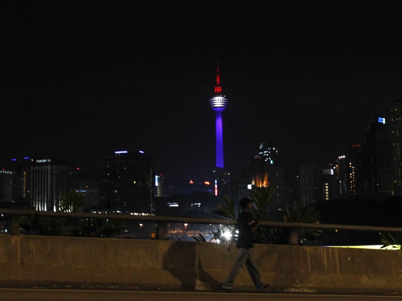 A man walks past one of Malaysia's landmark building, Kuala Lumpur Tower illuminated with the colors of the French flag in Kuala Lumpur, Malaysia, Saturday, Nov. 14, 2015. Photo: AP