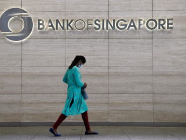 A woman walks past a Bank of Singapore office in Singapore on March 31, 2022.