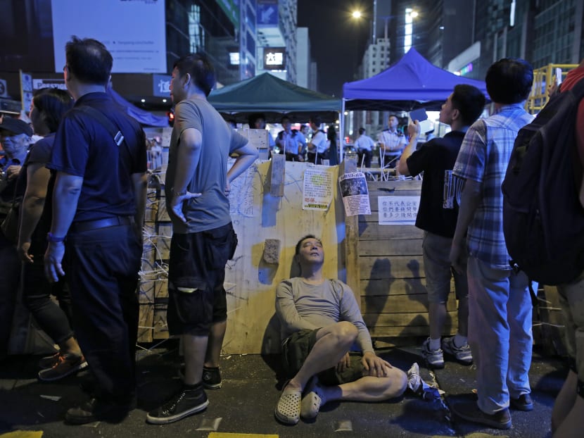 A man takes a rest in front of a barricade on a main road in the occupied area of the Mong Kok district Hong Kong, Oct 25, 2014. Photo: AP