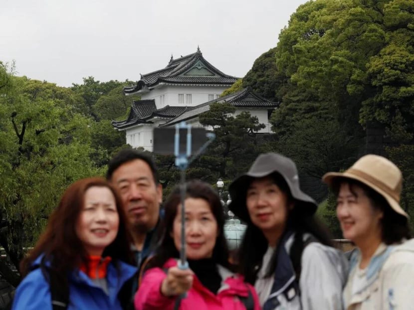 Chinese tourists take photos in front of the Imperial Palace in Tokyo, Japan.