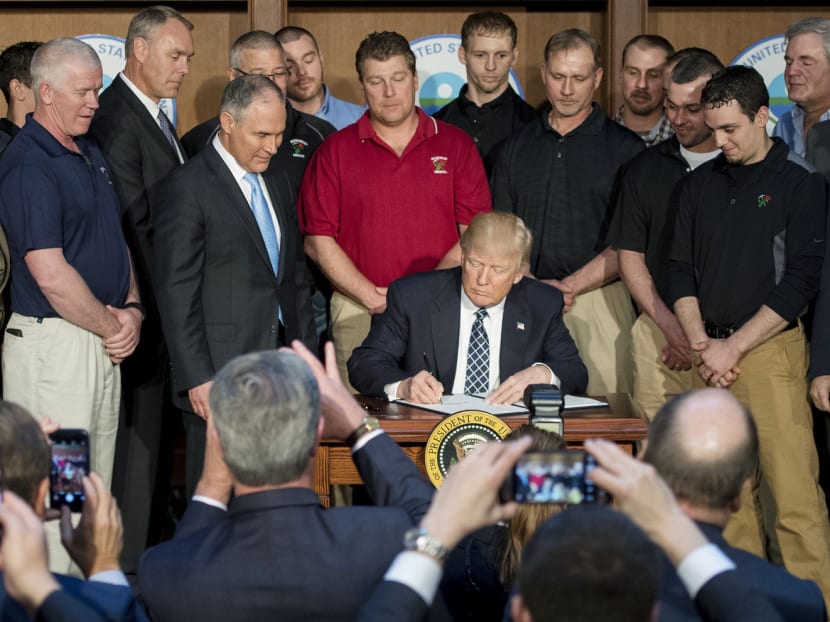 Surrounded by miners, President Trump signs the Energy Independence Executive Order at the Environmental Protection Agency headquarters on Tuesday. Photo: AFP