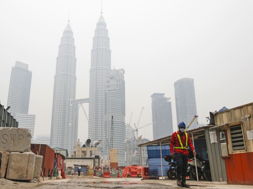 A construction worker in mask walks in front of Malaysia's landmark building, Petronas Twin Towers shrouded with haze in Kuala Lumpur, Malaysia, Oct 21, 2015.  Photo: AP
