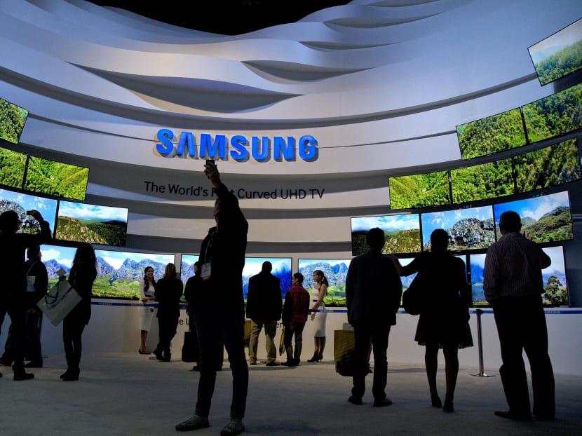 Trade show attendees take in a display of Samsung curved UHD TVs at the International Consumer Electronics Show, in Las Vegas.  Samsung reports quarterly earnings on Friday, Jan 24, 2014. Photo: AP