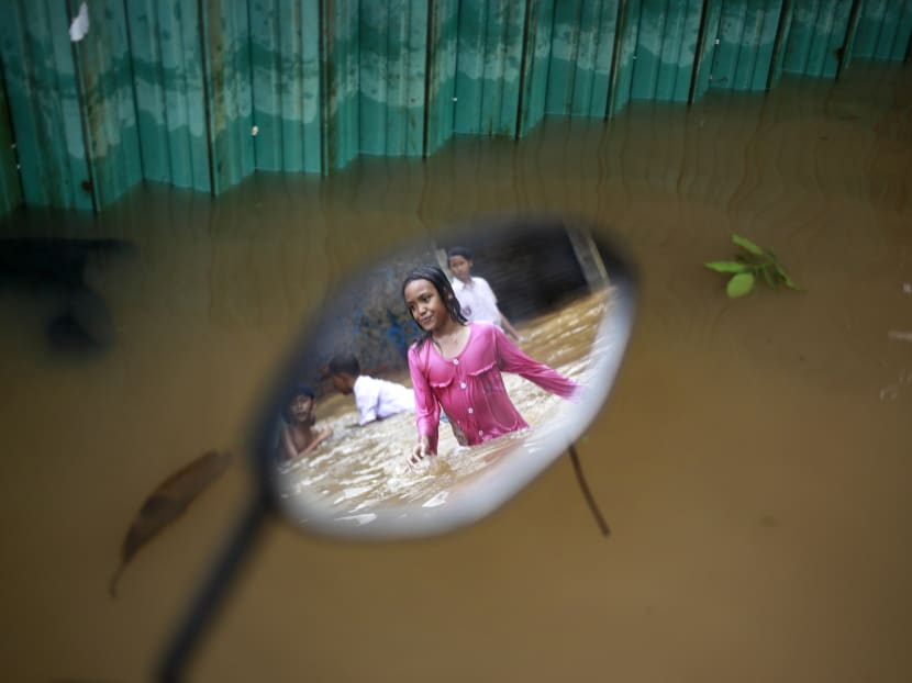 The reflection of a girl is seen on a mirror of a motorcycle left at a flooded neighbourhood in Jakarta on Feb 21, 2017. Torrential rains in the Indonesian capital have overwhelmed drains and flooded roads and thousands of homes. Photo: AP