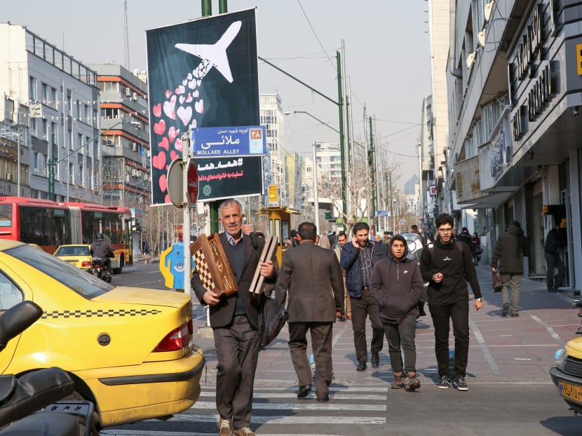 Iranians walk past a poster honouring the victims of a Ukrainian passenger jet accidentally shot down in the capital last week, in front of the Amirkabir University in the capital Tehran.