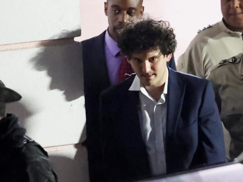 Sam Bankman-Fried, who founded and led FTX until a liquidity crunch forced the cryptocurrency exchange to declare bankruptcy, is escorted out of the Magistrate Court building after his arrest, in Nassau, Bahamas on Dec 13, 2022. 