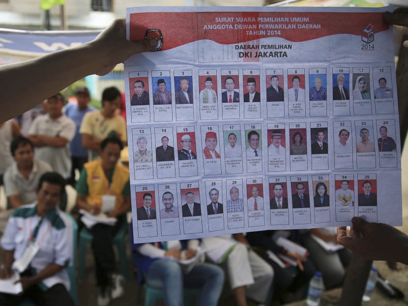 People watch as electoral officials show ballot papers during vote counting at a polling station in Jakarta. Photo: REUTERS