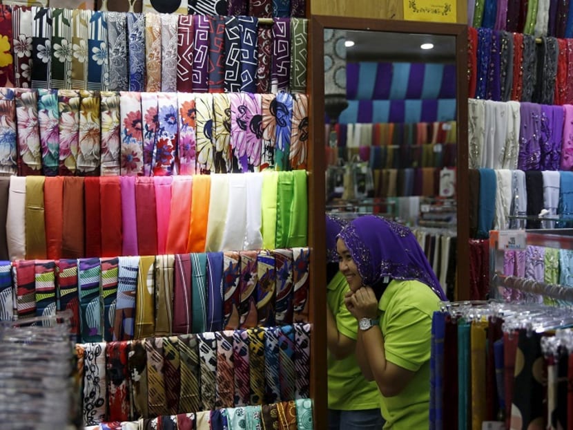 A woman trying on a headscarf in Kuala Lumpur. Malaysian Tourism and Culture Minister Nazri Aziz has hit out at a policy by some Malaysian hotels barring Muslim female frontline staff from wearing headscarves, describing the move as “imbecilic” and “unconstitutional”. Photo: Reuters