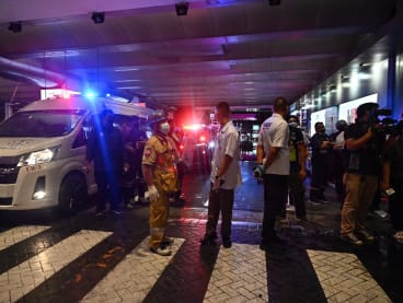 Police, rescue workers and media representatives stand next to an ambulance outside Siam Paragon shopping centre in Bangkok on Oct 3, 2023, following a shooting incident in the mall.