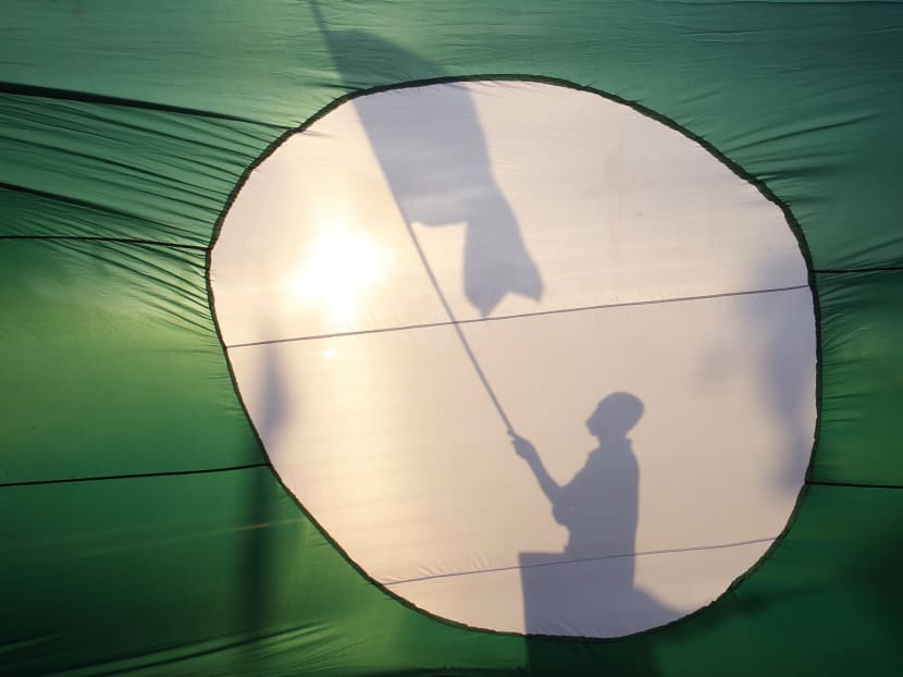 A supporter of opposition Parti Islam se-Malaysia (PAS) is silhouetted on its giant flag. Supporters may not vote for the party at the general election due to confusion over PAS's close ties with Umno. Photo: Reuters