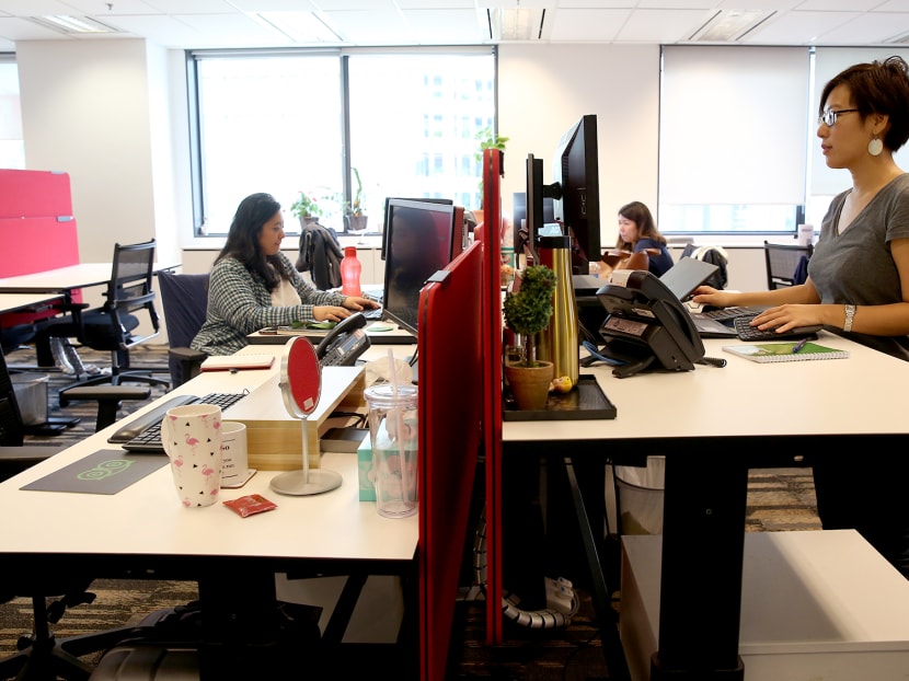 A staff at TripAdvisor's Singapore office in Manulife Tower using a height-adjustable desk.