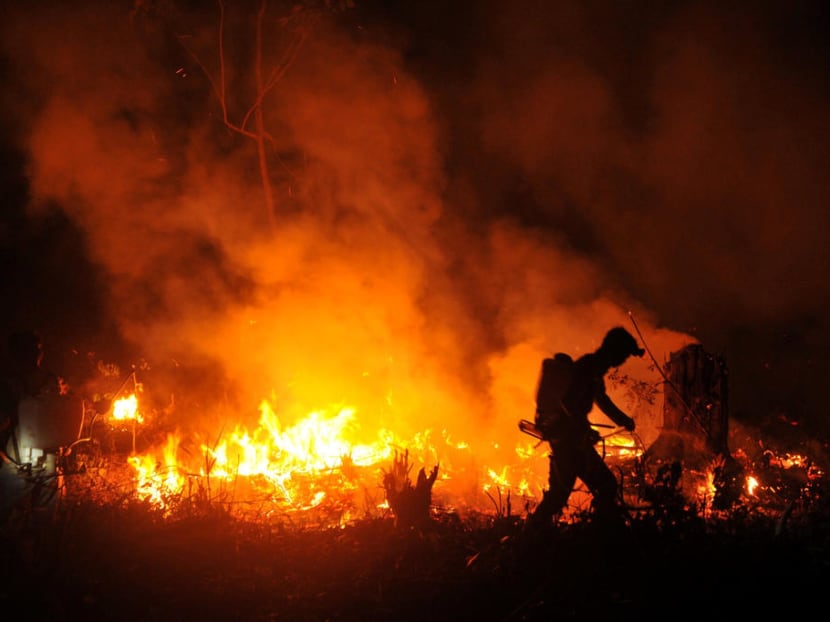 An officer tries to extinguish fire on a land in Musi Banyuasin near Palembang in South Sumatra, Indonesia.