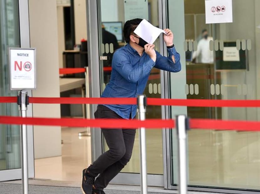 Leonard Teo Min Xuan, an administrator behind obscene Telegram chat group SG Nasi Lemak, hiding his face at the State Courts on May 4, 2021.