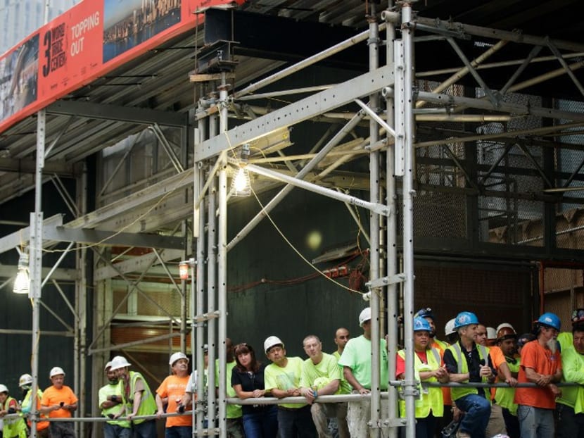 Construction workers gather at the base of 3 World Trade Center to watch before a concrete bucket is lifted to the top of the building during a topping off ceremony for 3 World Trade Center, June 23, 2016 in New York City. Photo: AFP