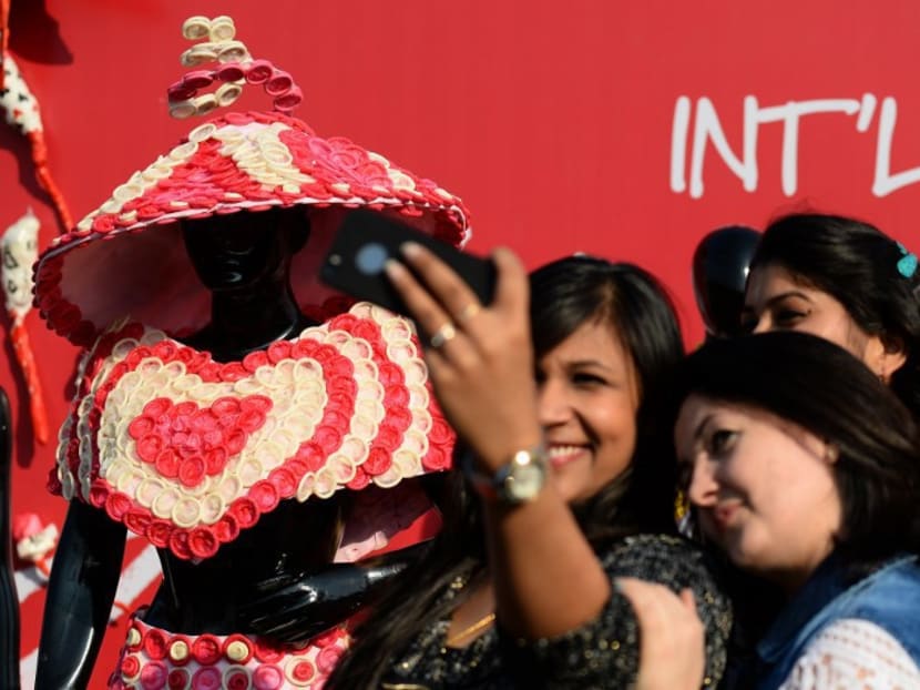 Women take a selfie with a mannequin wearing a dress made of condoms during an event to mark International Condom Day in February. India’s government declared this week that condom commercials are “indecent” viewing for children and restricting them to the hours of 10pm to 6am. Photo: AFP