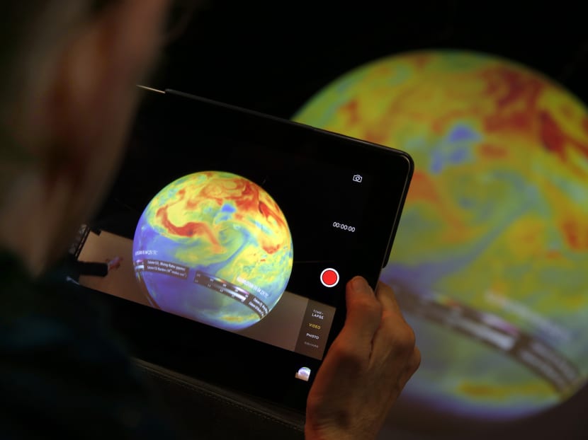 A woman takes a picture of a globe at the COP21, the United Nations Climate Change Conference. Photo: AP A woman takes a picture of a globe at the COP21, the United Nations Climate Change Conference. Photo: AP