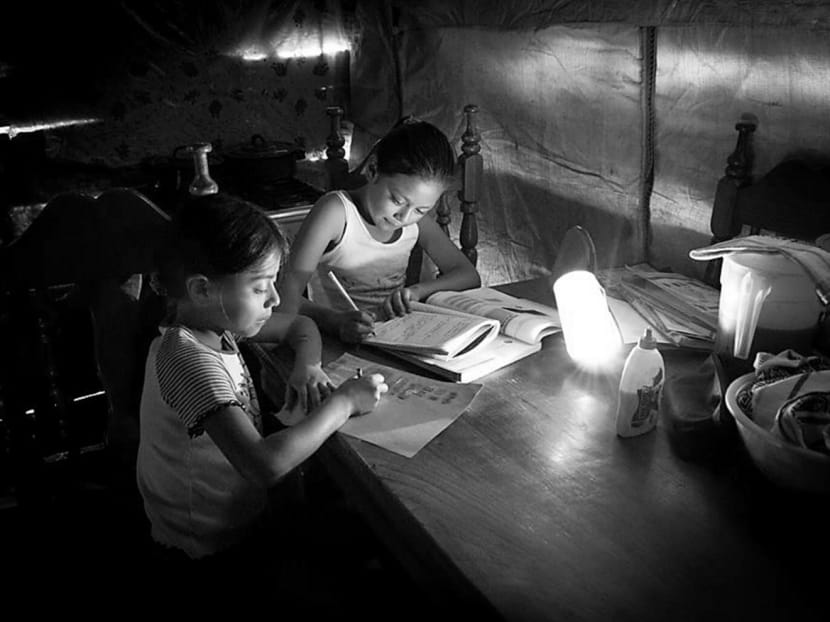 Two students in Guatemala using a lamp designed by d.light while studying. d.light is a social venture that has developed a range of low-cost, sturdy lamps. Photo: D.Light Design Facebook page