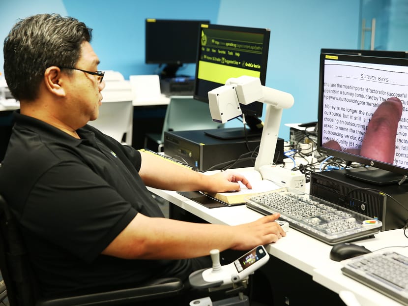 Mr Colin Loh, a tech support staff at the Tech Able centre, showing how a magnifier works. Photo: Nuria Ling/TODAY