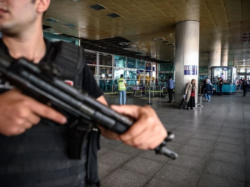 A Turkish anti-riot police officer stands guard as people walk past near the explosion site on June 29, 2016 at Ataturk airport International arrival terminal in Istanbul, after a suicide bombing and gun attack killed 42 people. Photo: AFP