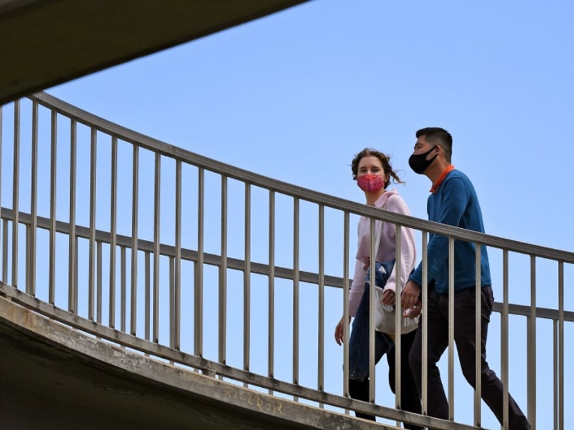 People wearing face masks cross a pedestrian bridge in the Melbourne suburb of St Kilda on Oct 26, 2020 as Australian health officials reported no new coronavirus cases or deaths in Victoria state, which has spent months under onerous restrictions after becoming the epicentre of the country's second wave.