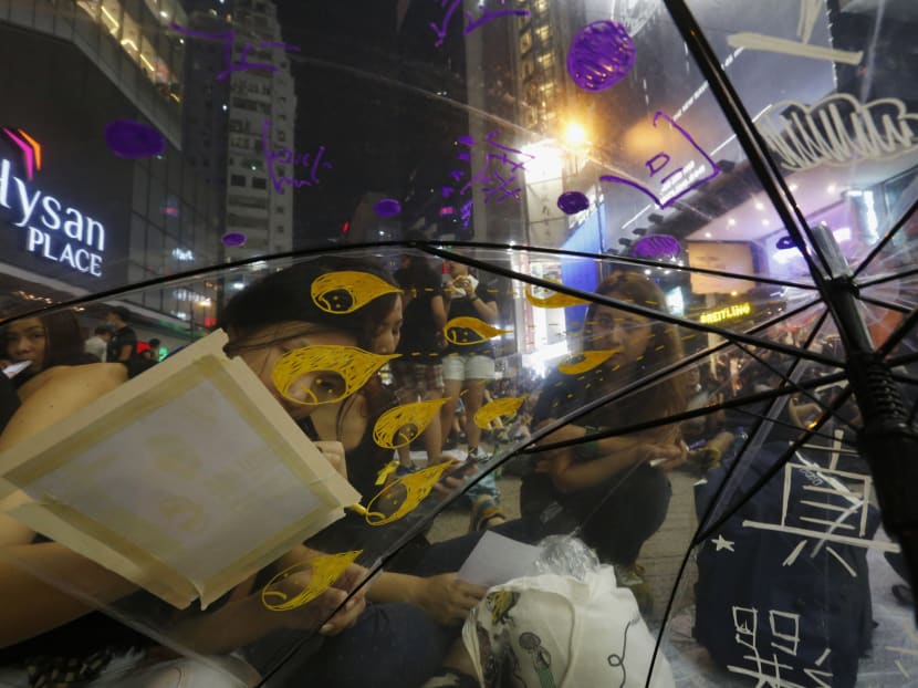 A protester writing "true elections" (in white) on an umbrella during a rally at the main road at the Causeway Bay shopping district in Hong Kong on Sept 30, 2014. Photo: Reuters