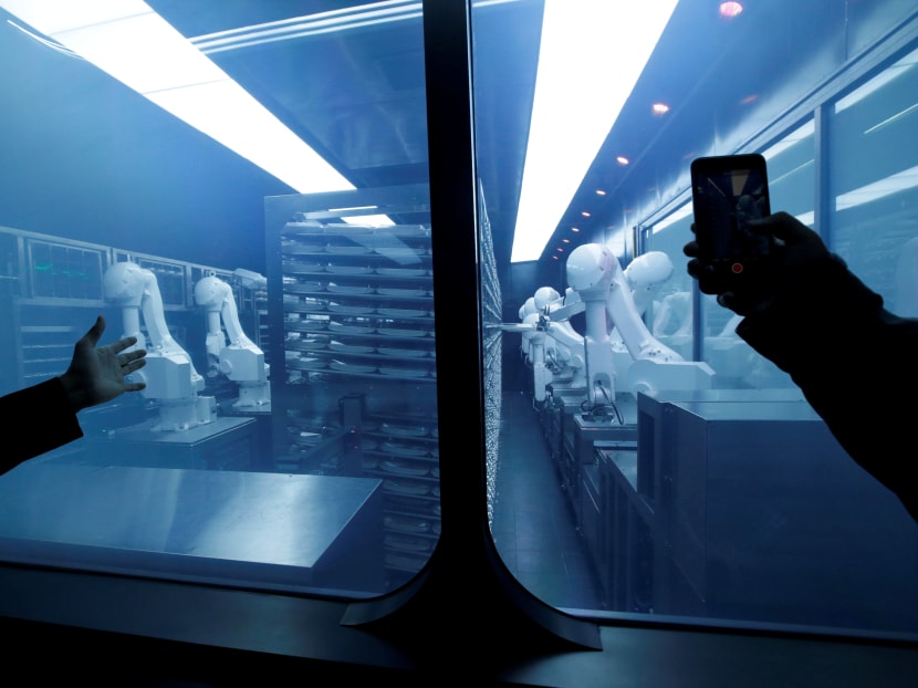 A customer takes a picture as robotic arms collect pre-packaged dishes from a cold storage, done according to the diners' orders, at Haidilao's new artificial intelligence hotpot restaurant in Beijing.