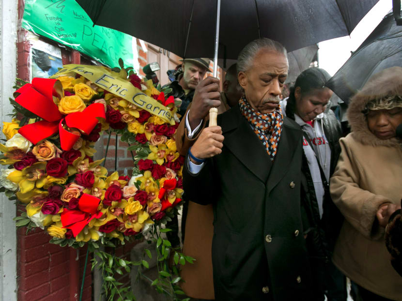 The Rev. Al Sharpton is accompanied by Esaw Garner, center, wife of Eric Garner, who died in a chokehold incident with a New York City Police officer, and Gwen Carr, mother of the deceased, as he places a wreath at the scene of the occurrence, in the Staten Island borough of New York,  Saturday, Dec. 6, 2014. Photo: AP