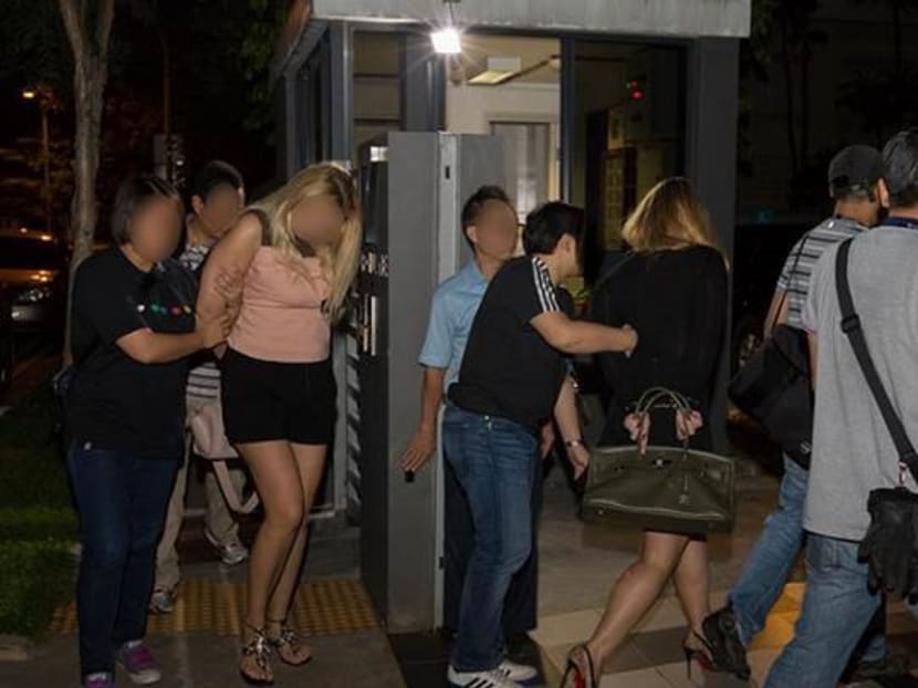 Police arresting two of the women in the raids on Thursday (May 4). Photo: Singapore Police Force