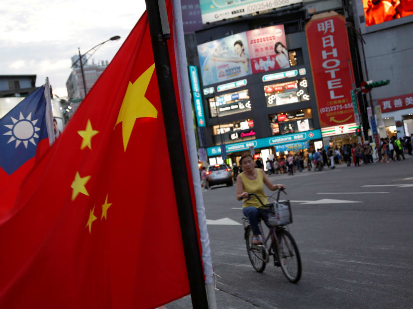 A woman rides a bike past Taiwan and China national flags. Taiwan says it will dole out more incentives aimed at retaining talented workers and strengthening protection for company trade secrets, in a bid to counter China’s efforts to draw investment by Taiwan companies. Photo: Reuters