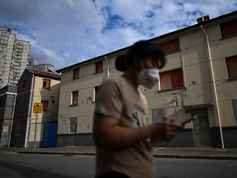 This photo taken on June 22, 2022 shows a woman walks past a sealed building marked for demolition in the Laoximen neighbourhood of Shanghai's Huangpu district. This photo taken on June 22, 2022 shows a woman walks past a sealed building marked for demolition in the Laoximen neighbourhood of Shanghai's Huangpu district.