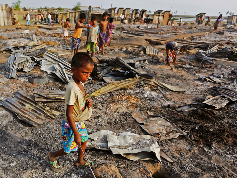 A boy walking among debris after fire destroyed shelters at a camp for internally displaced Rohingya Muslims. Photo: Reuters