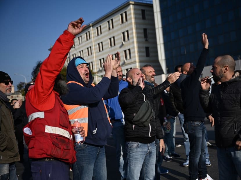 Workers react as they block port operations at the Etiopia gate (Varco Etiopia) in the port of Genoa, Liguria, on October 15, 2021 as new coronavirus restrictions for workers come into effect. Workers react as they block port operations at the Etiopia gate (Varco Etiopia) in the port of Genoa, Liguria, on October 15, 2021 as new coronavirus restrictions for workers come into effect.