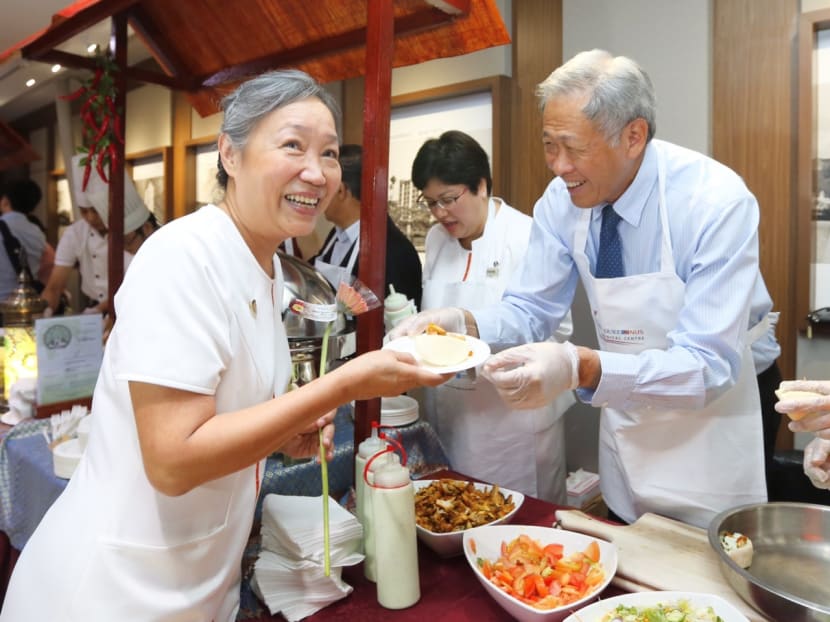 Defence Minister Dr Ng Eng Hen serving local delicacies to SingHealth nurses, together with Group Chief Nurse Dr. Tracy Ayre, SingHealth Chairman Mr Peter Seah and senior management. Photo: Ernest Chua/TODAY