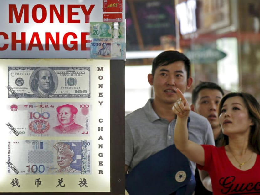 A money changer displaying a poster of the United States dollar bill, Chinese yuan and Malaysia ringgit. The exchange rate on offer at some counters in Chinatown and Raffles Place was about 5.08 Chinese yuan for S$1.