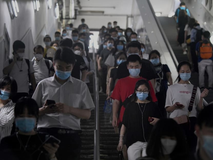 Passengers wearing face masks walk through a subway station in Beijing on June 15, 2020.