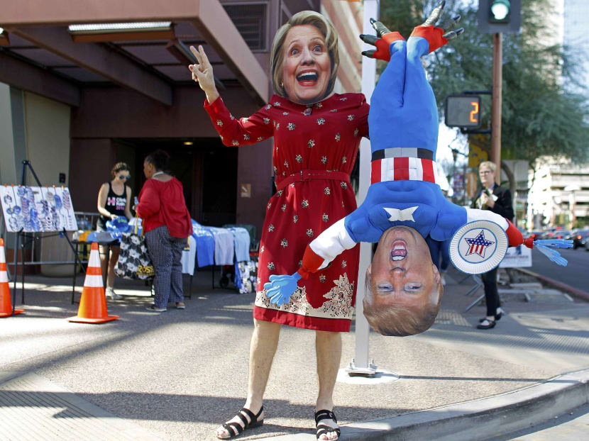 A man wears a mask depicting Democratic U.S. presidential candidate Hillary Clinton while holding a doll depicting Republican presidential nominee Donald Trump in Phoenix, Arizona October 20, 2016. Photo: Reuters