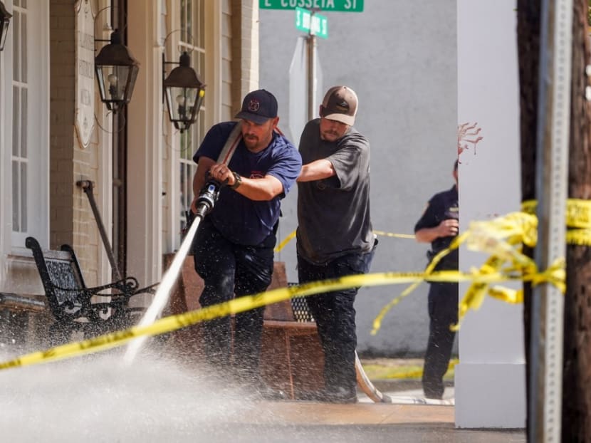 A bloody handprint can be seen as fire fighters use a hose to wash down the scene of a shooting Saturday night at the Mahogany Masterpiece dance studio on April 16, 2023 in Dadeville, Alabama.