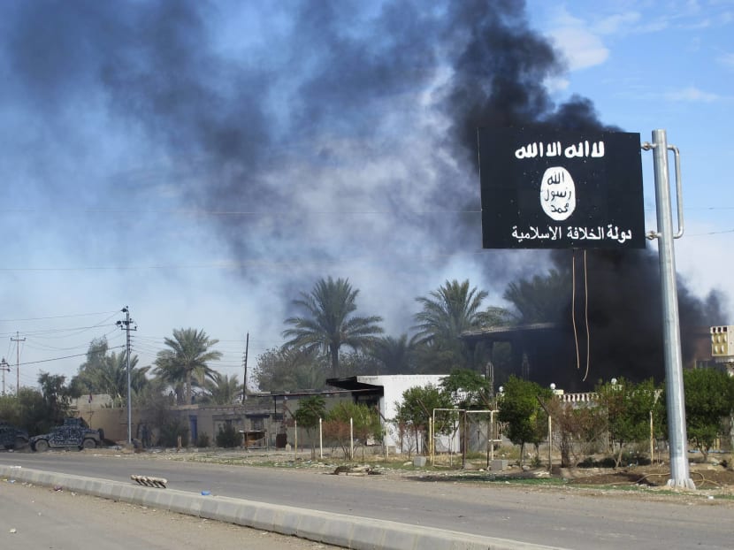 Smoke raises behind an Islamic State flag after Iraqi security forces and Shiite fighters took control of Saadiya in Diyala province from Islamist State militants. Photo: Reuters