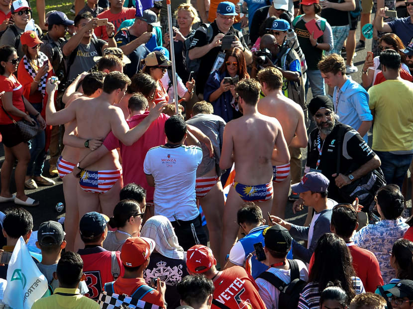 This picture taken on Oct 2, 2016, shows spectators with swimwear bearing a Malaysin flag posing for pictures during the Formula One Malaysian Grand Prix in Sepang. Photo: AFP