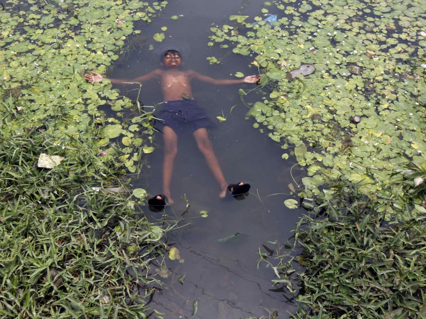 A boy floats in a pond to cool off on a hot summer day on the outskirts of Kolkata, India, April 28, 2016. Photo: Reuters