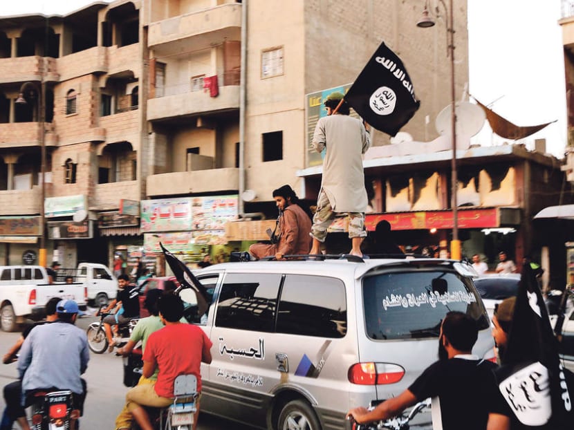 Members loyal to the Islamic State in Iraq and the Levant (ISIL) wave ISIL flags as they drive around Raqqa in 2014. A new report says the decline in ISIL's numbers corresponds with a continuing fall in the number of terrorism deaths worldwide.