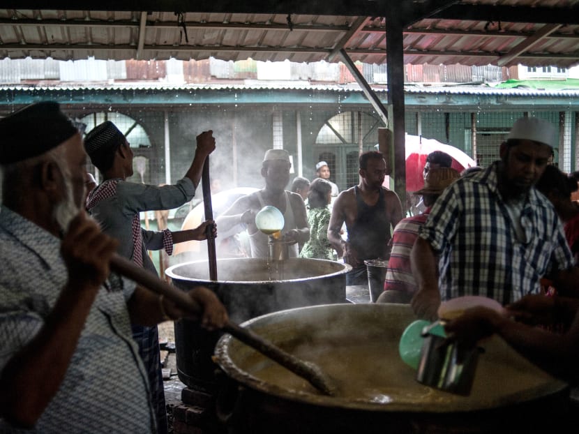 In this photo taken on May 30, 2017, men use wooden paddles to stir huge steaming vats of daal as they prepare to feed members of the Muslim community in Yangon when they break their fast during the holy month of Ramadan. Huddled under umbrellas to escape a thundering monsoon downpour, dozens of Muslims stood in line at a mosque in Yangon waiting for a small portion of rice and curry to break their Ramadan fast. Photo: AFP