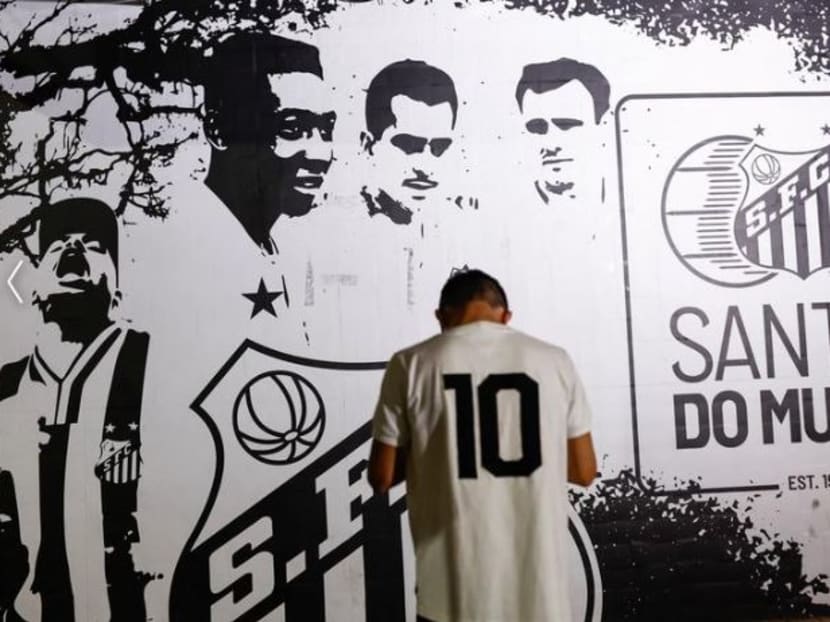 A person stands in front of an image depicting Brazilian soccer legend Pele as people gather to mourn his death, in Santos, Brazil, Dec 29, 2022.