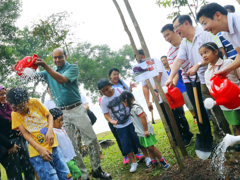 DPM Tharman Shanmugaratnam giving student Aw Jun Le an unexpected shower during a tree-planting activity at the planned Jurong Lake Gardens @ PUB installation at Yuan Ching Road. Photo: Ernest Chua