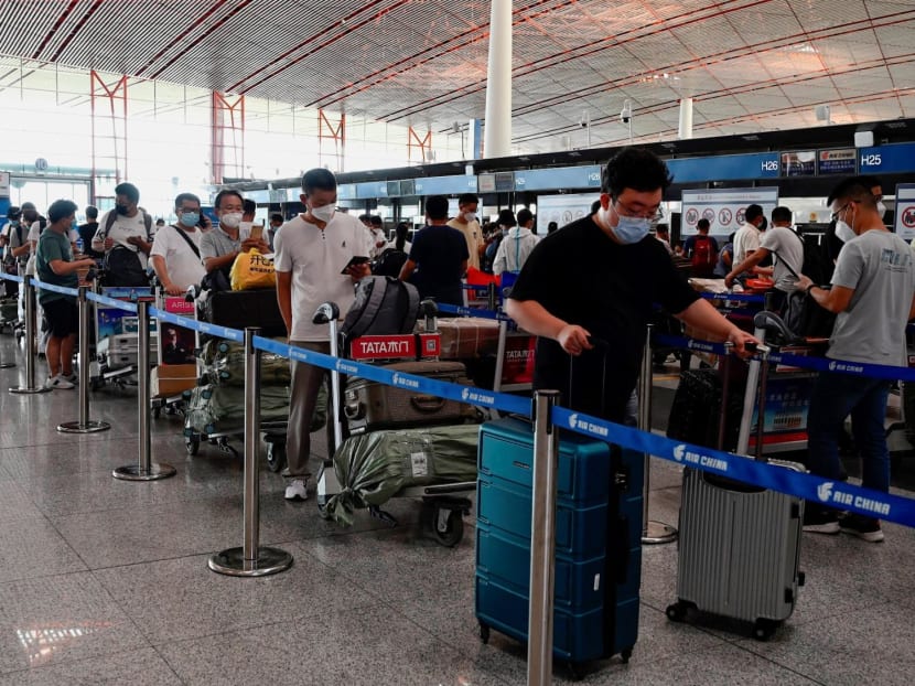 Travellers wearing face masks queuing at a check-in area of Beijing’s Capital international airport, China, in August 2021.