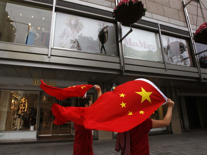 People carrying Chinese flags walk past a shopping mall.  Just as the United States throws up new barriers to cross-border commerce, its largest trading partner China is redoubling its efforts to seal free-trade agreements. Photo: Reuters