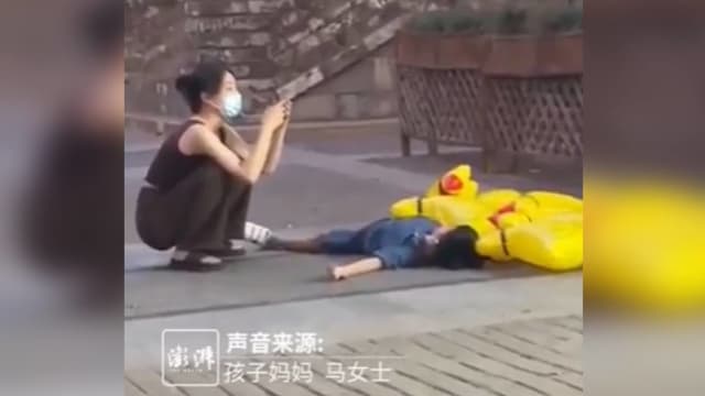 儿子躺地耍赖 中国妈妈淡定玩手机