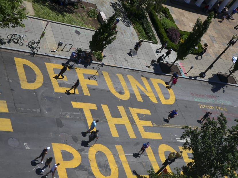 People walk down 16th Street near the White House, in Washington, DC, on June 8, 2020, after the words "Defund The Police" were painted on it.