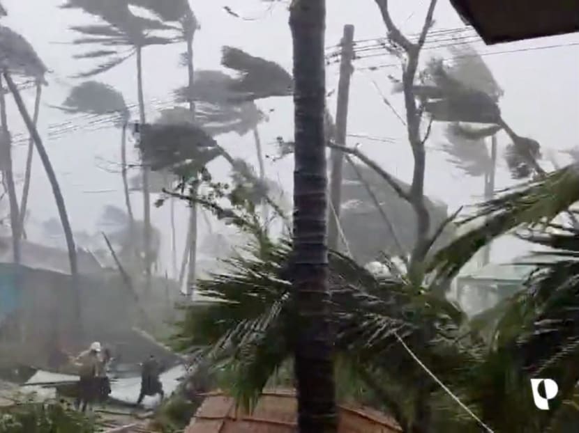 People walk near damaged structures amid strong winds and rain caused by Cyclone Mocha in Sittwe, Myanmar in this screengrab from a handout video released on May 14, 2023